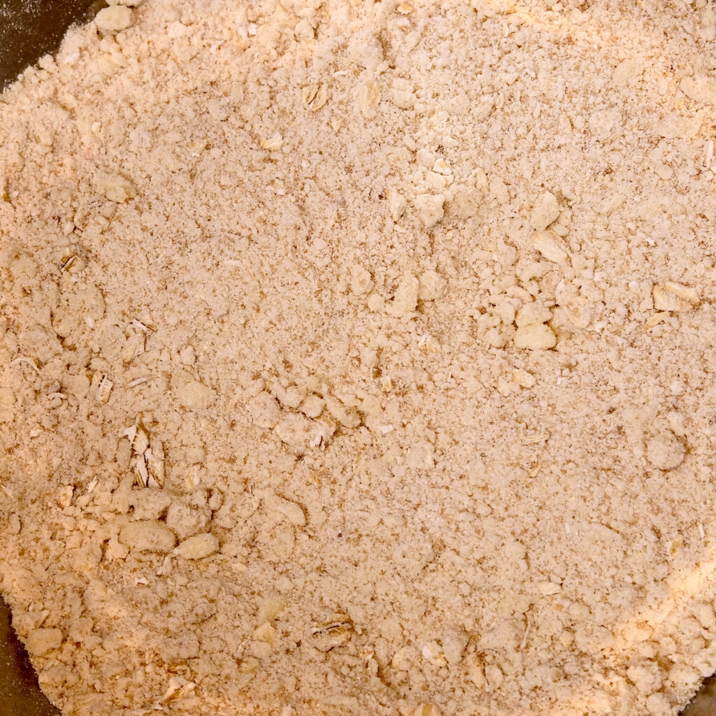 Overhead shot of butter blended into Oat mixture in stainless steel mixing bowl.