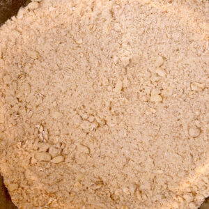 Overhead shot of butter blended into flour mixture in stainless steel mixing bowl.