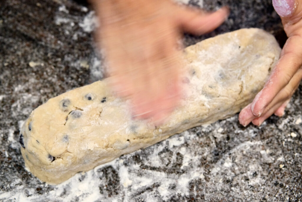 Hand giving final pat and shaping of scone dough log.