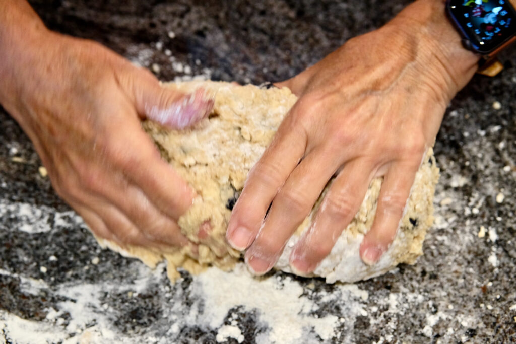 Two hands depicting how to bring dough together.
