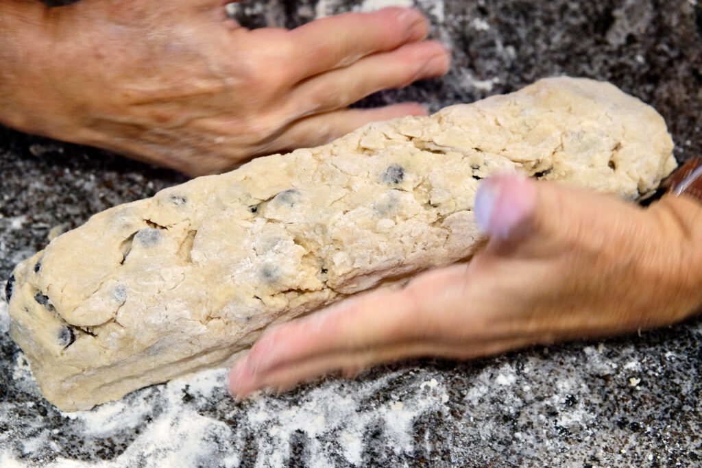 Two hands showing how to form dough into rectangular log.