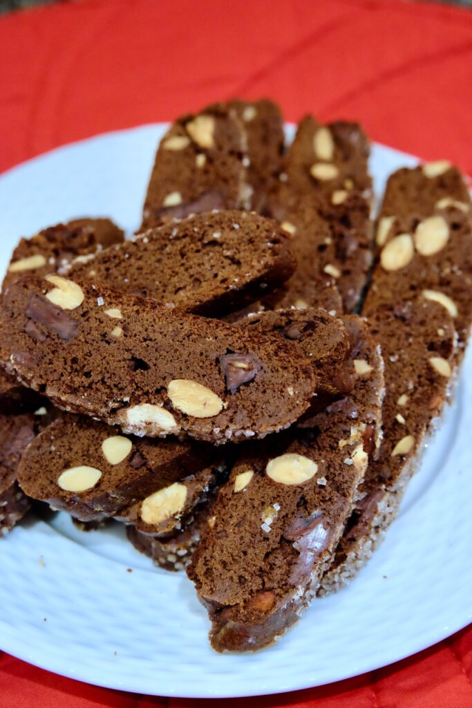 Double chocolate biscotti set on white plate with red linen in background.