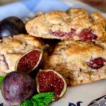 Fresh fig scones served on a blue and white plate with whole and cut figs in foreground